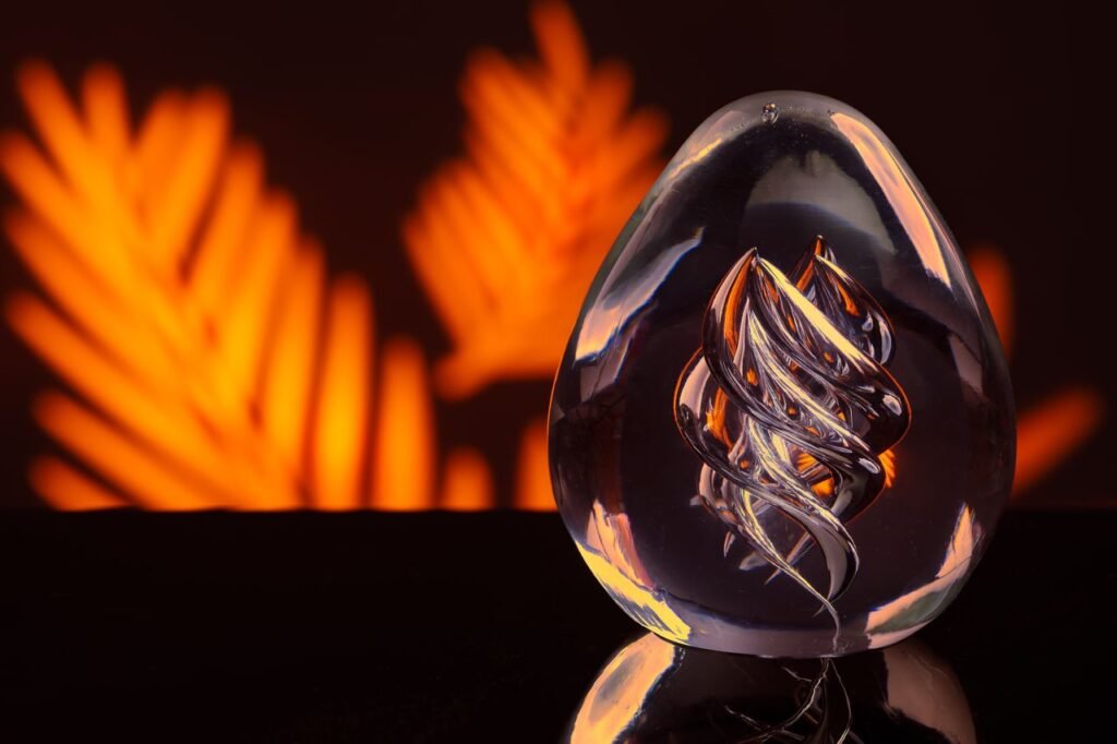 Close-up of a glass sculpture with intricate design against a vibrant orange background.