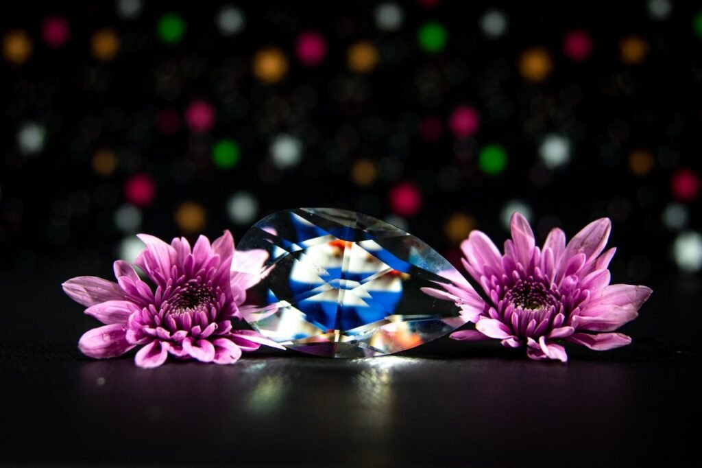 A dazzling crystal diamond surrounded by pink flowers with a bokeh background.
