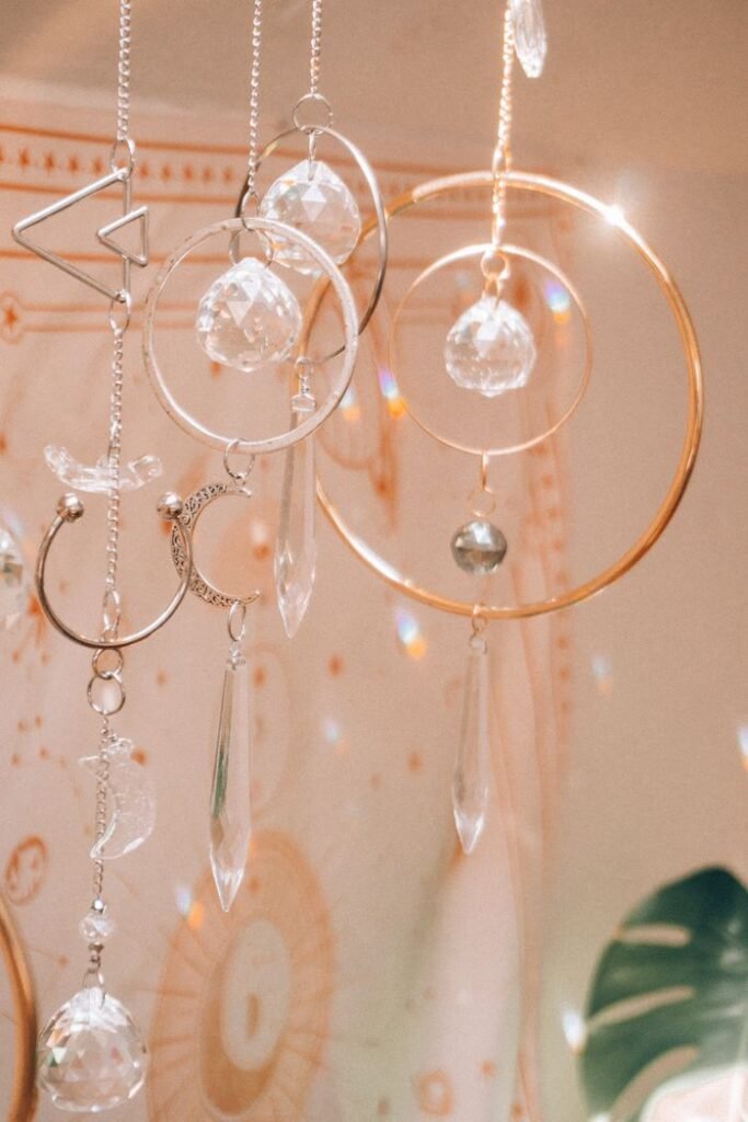 Close-up of hanging crystal ornaments with astrology symbols in soft light.