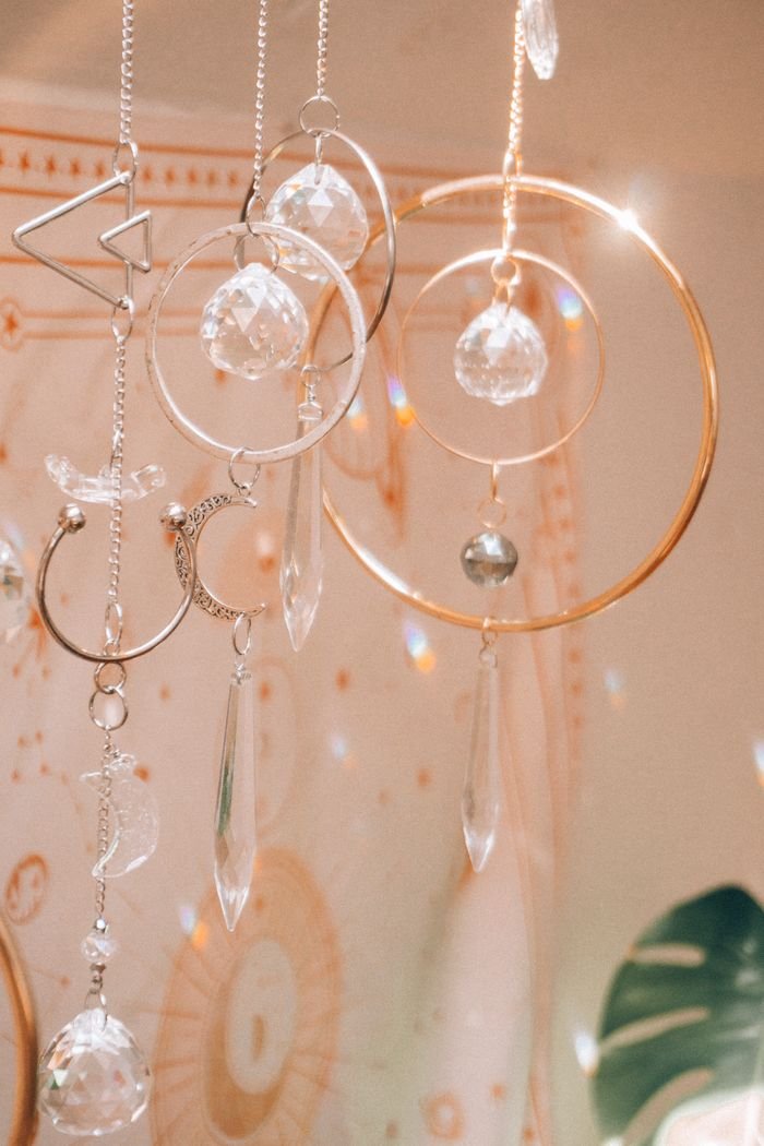 Close-up of hanging crystal ornaments with astrology symbols in soft light.